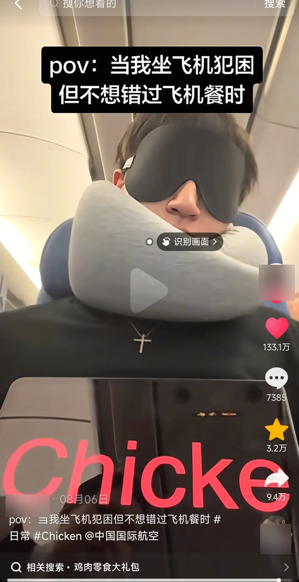 A young man asleep on a plane in a black sleep mask and grey neck pillow, a tablet on his lap showing the word Chicken in huge red letters, cut off at Chicke